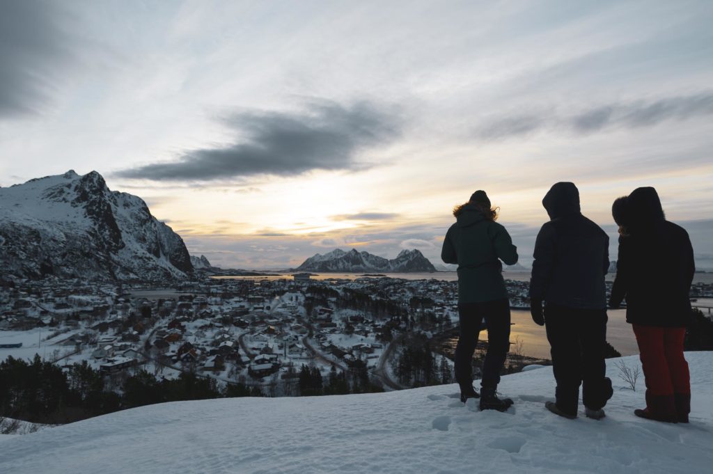 Tre unge mennekser foran utsikt over hav og fjell i Lofoten