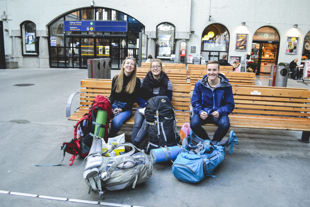 Backpackere smiler mens de venter på togstasjon