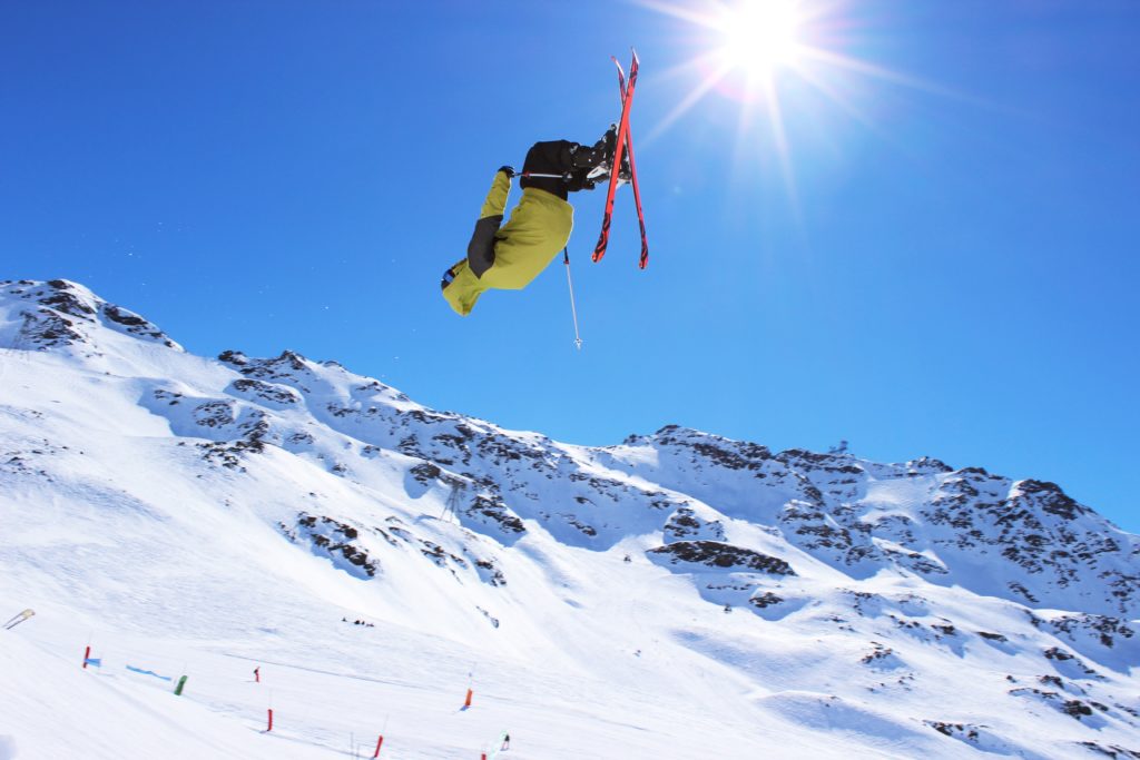 Skikjører trikser på hopp i alpefjell