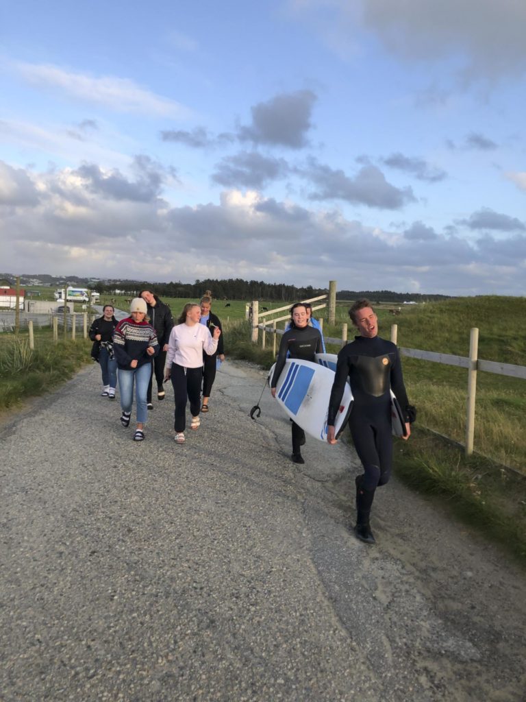 Gruppe unge mennesker på vei til stranda med surfebrett