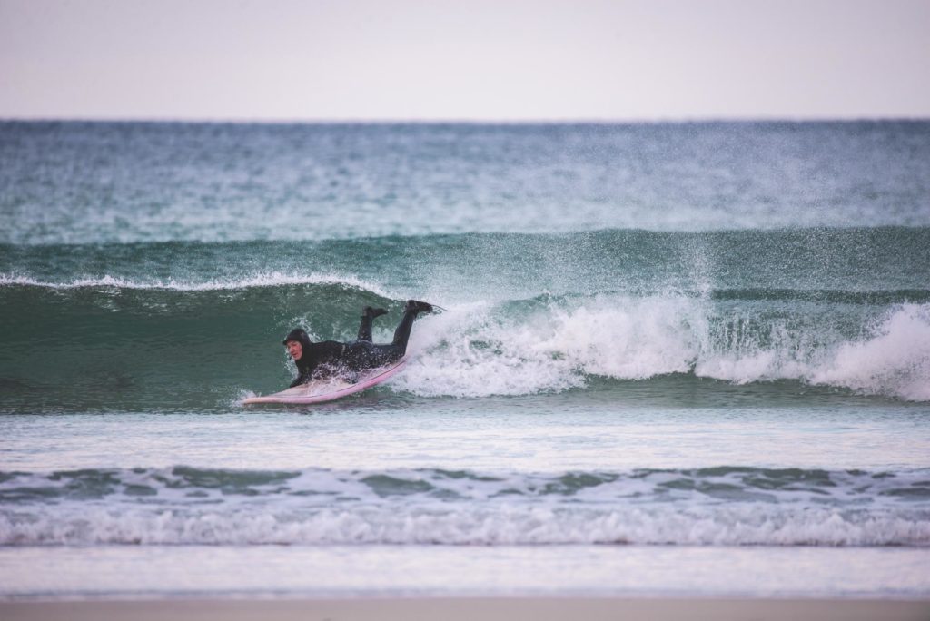 Surfer i vannet på surfebrett
