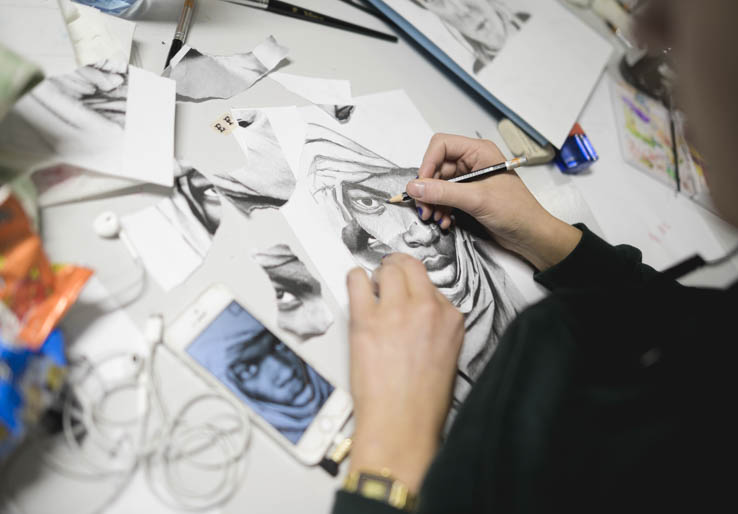 Arbeidsbord med tegnesaker og et kunstverk i prosess