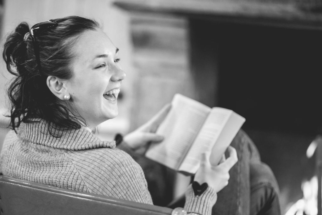 Ung kvinne leser bok og smiler
