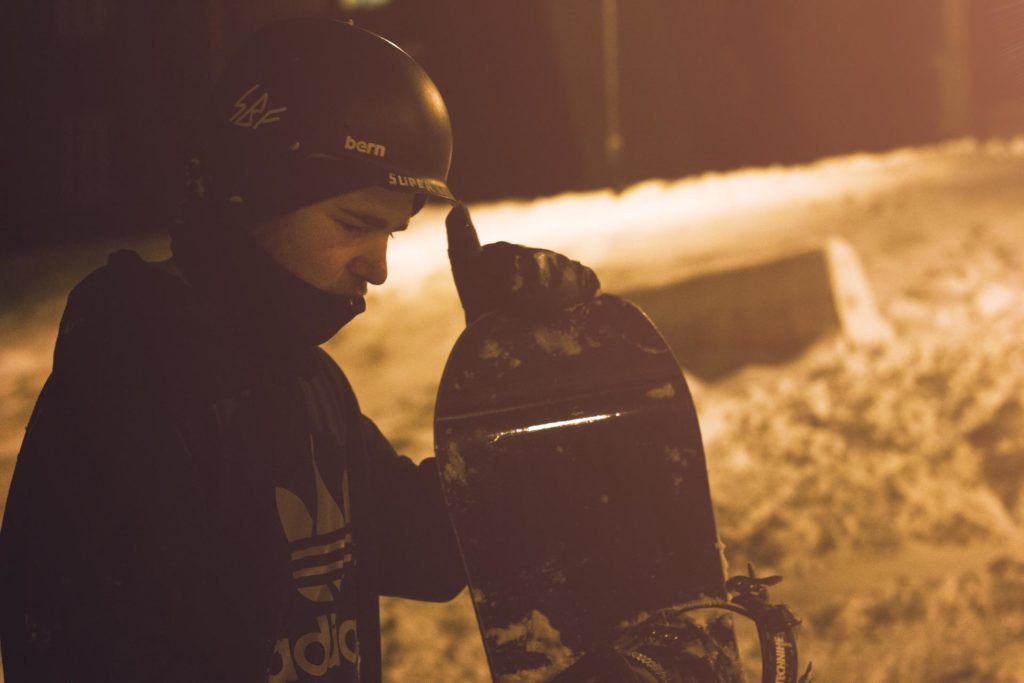 Ung mann poserer med snowboard