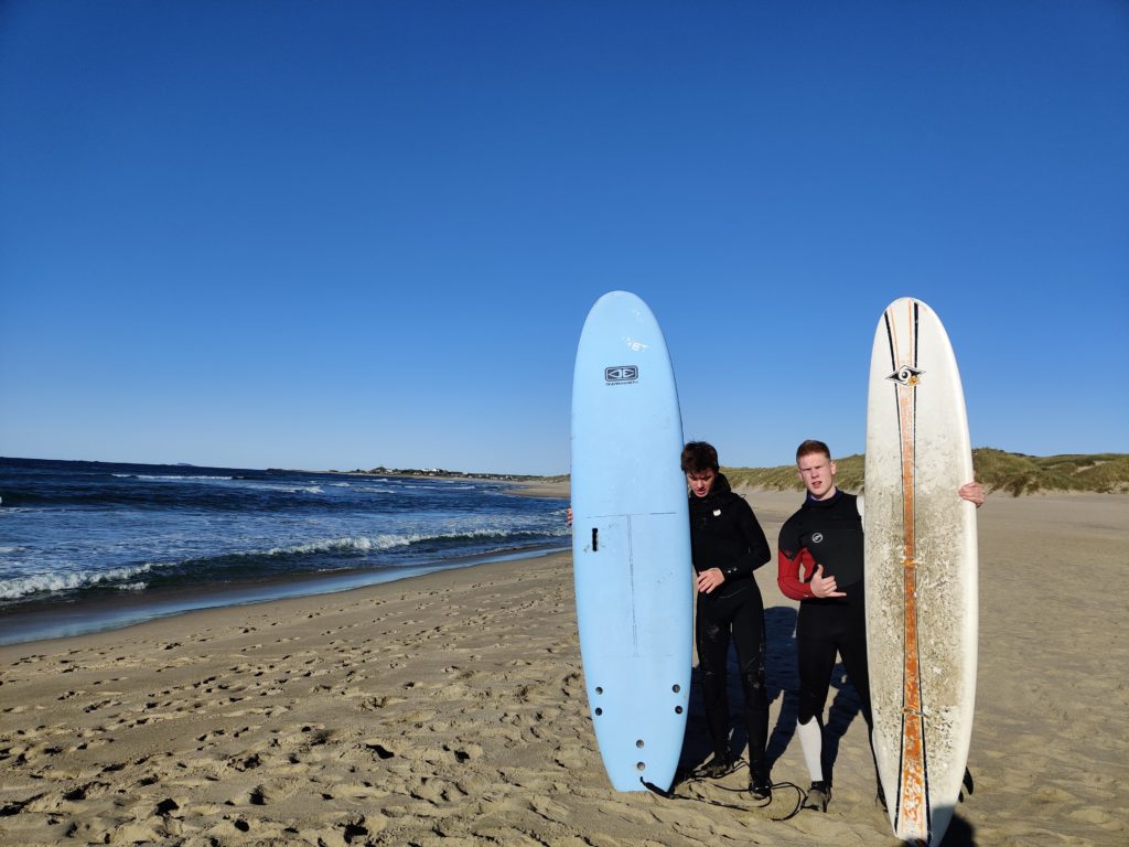 Unge menn poserer med surfebrett